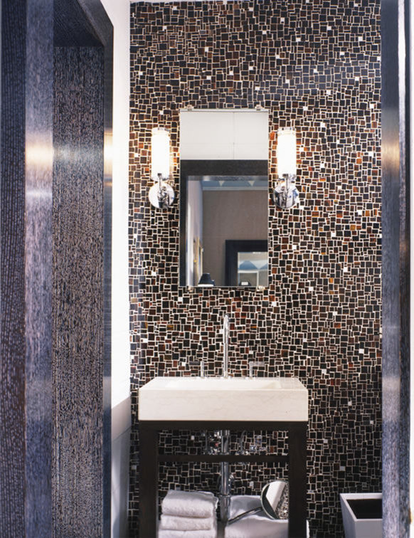 Photo of a large modern cloakroom in New York with freestanding cabinets, brown cabinets, a two-piece toilet, brown tiles, glass tiles, brown walls, marble flooring, a pedestal sink, limestone worktops and brown floors.