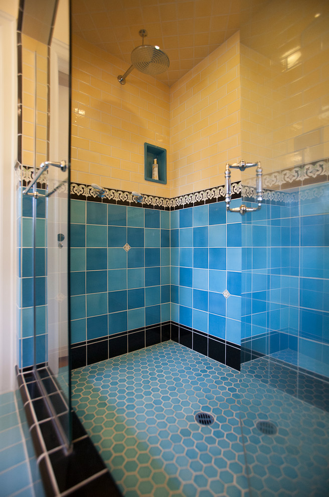 Modelo de cuarto de baño principal grande con ducha doble, sanitario de dos piezas, baldosas y/o azulejos azules, baldosas y/o azulejos de porcelana, paredes amarillas, suelo de baldosas de porcelana y lavabo con pedestal