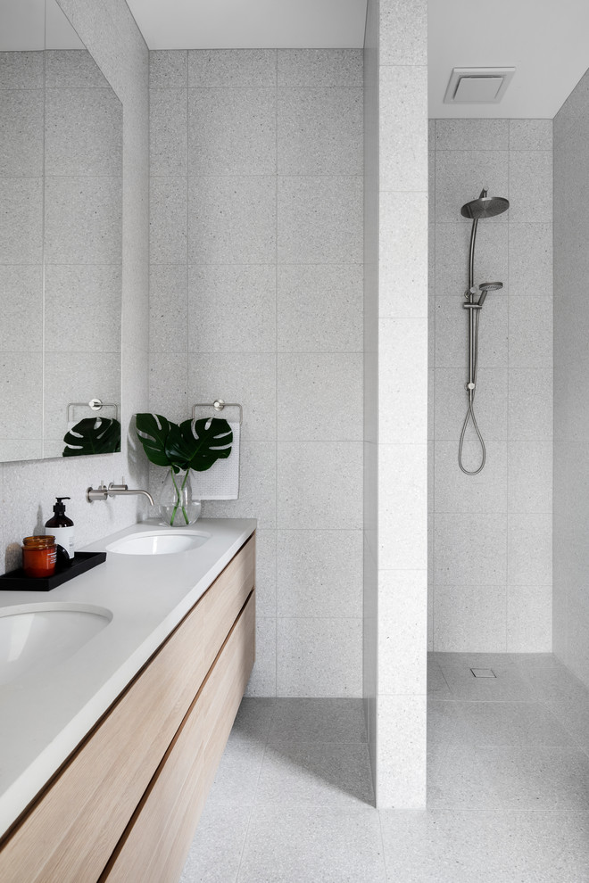 Modernes Badezimmer mit flächenbündigen Schrankfronten, hellen Holzschränken, Duschnische, grauen Fliesen, Unterbauwaschbecken, grauem Boden, offener Dusche und weißer Waschtischplatte in Melbourne