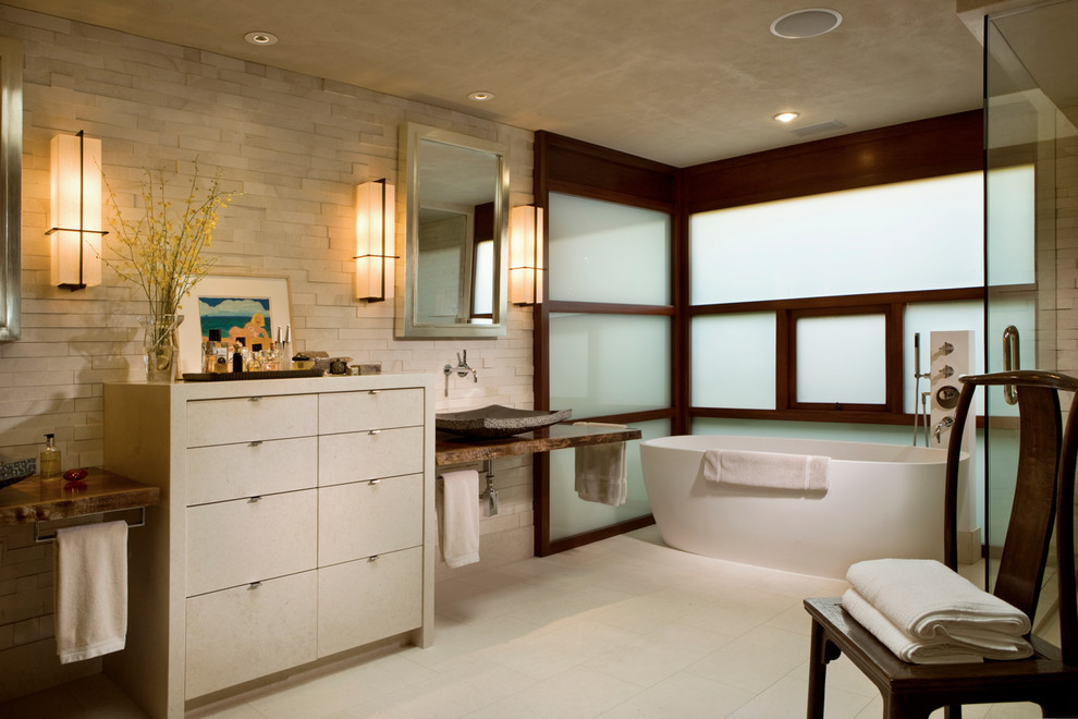 Diseño de cuarto de baño rectangular actual con bañera exenta, lavabo sobreencimera y piedra