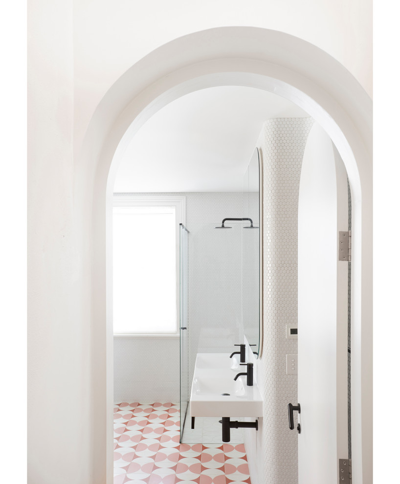 Inredning av ett minimalistiskt litet en-suite badrum, med ett fristående badkar, en hörndusch, en toalettstol med hel cisternkåpa, vit kakel, mosaik, vita väggar, cementgolv, ett väggmonterat handfat, rosa golv och dusch med gångjärnsdörr