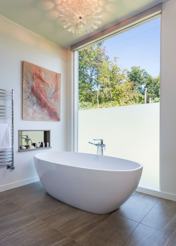 Réalisation d'une grande salle de bain principale design avec une baignoire indépendante, un mur blanc, un sol en carrelage de porcelaine et un sol marron.
