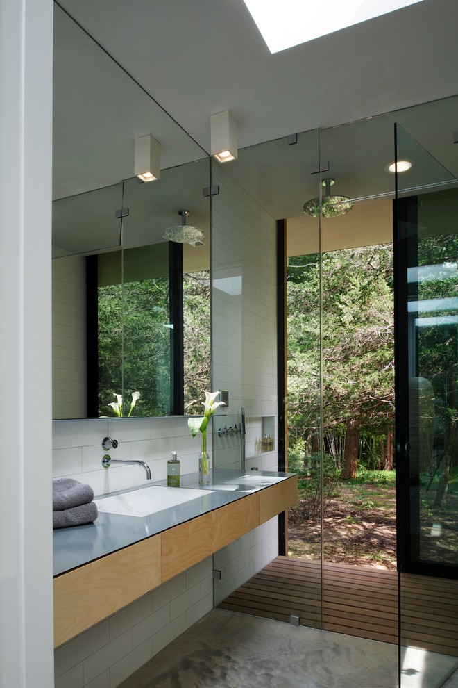 Aménagement d'une salle de bain moderne en bois clair avec un placard à porte plane, une douche à l'italienne, un carrelage blanc, sol en béton ciré et un lavabo encastré.