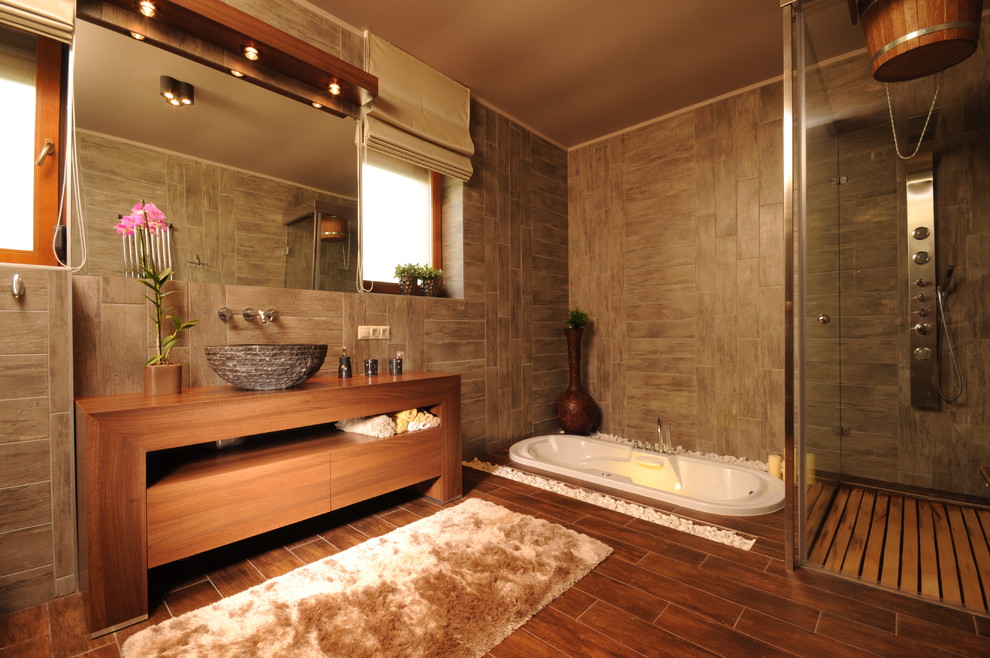 Foto på ett funkis badrum, med ett fristående handfat, skåp i mellenmörkt trä, ett platsbyggt badkar, en hörndusch och brun kakel