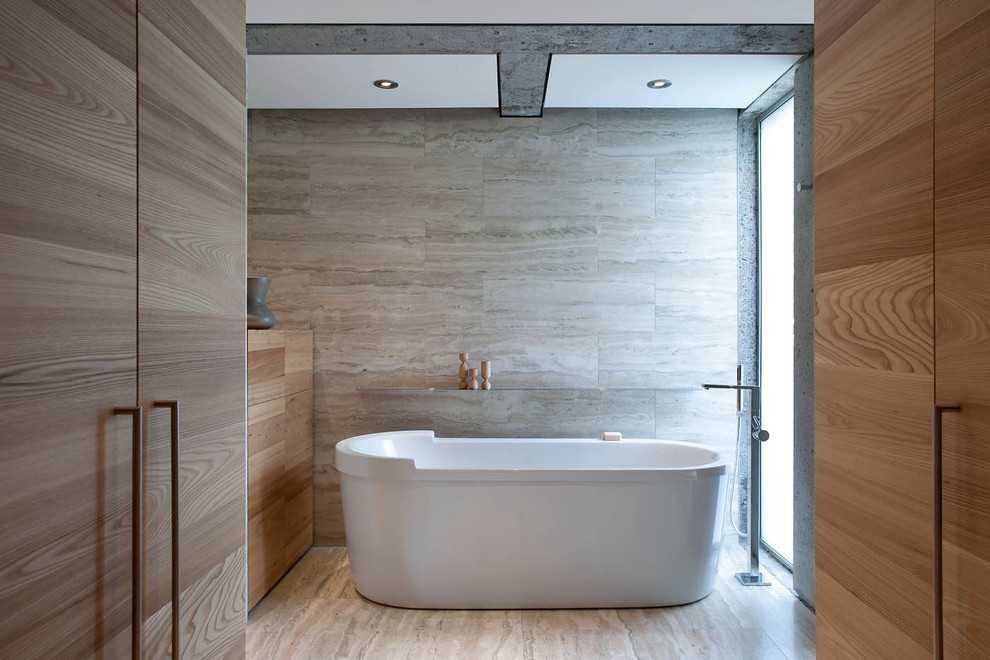 Réalisation d'une très grande salle de bain principale minimaliste en bois brun avec un placard à porte plane, une baignoire indépendante, un carrelage de pierre, un sol en travertin, un carrelage beige et un sol beige.