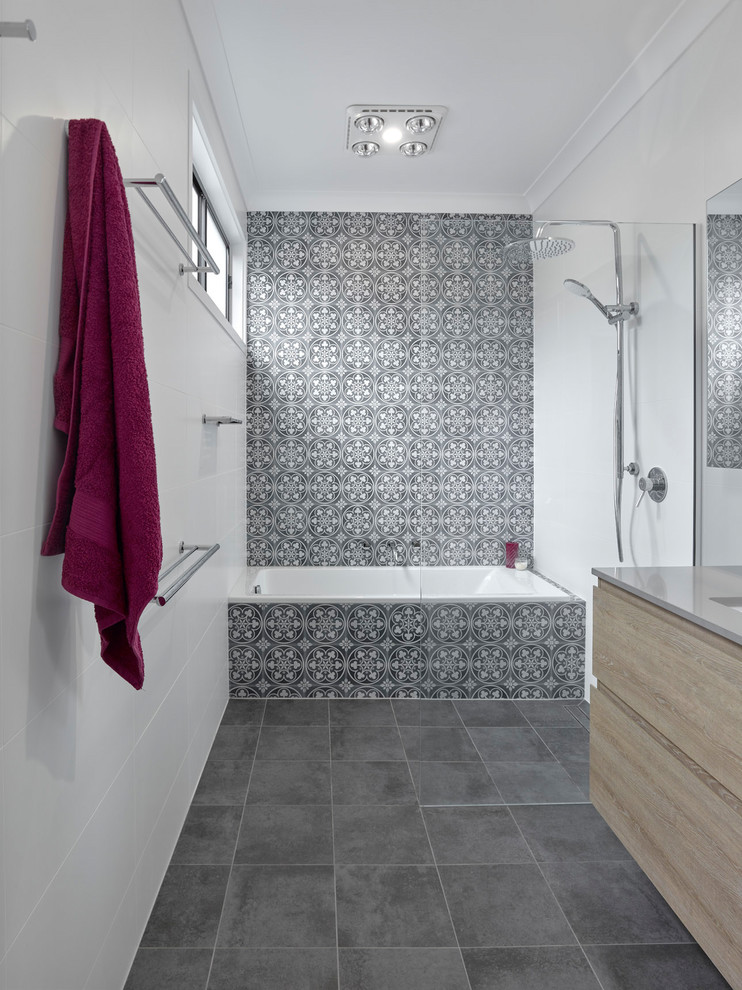 Inspiration for a small contemporary shower room bathroom in Other with flat-panel cabinets, light wood cabinets, a built-in bath, a walk-in shower, a two-piece toilet, blue tiles, ceramic tiles, multi-coloured walls, porcelain flooring, a submerged sink, engineered stone worktops, grey floors, an open shower and grey worktops.