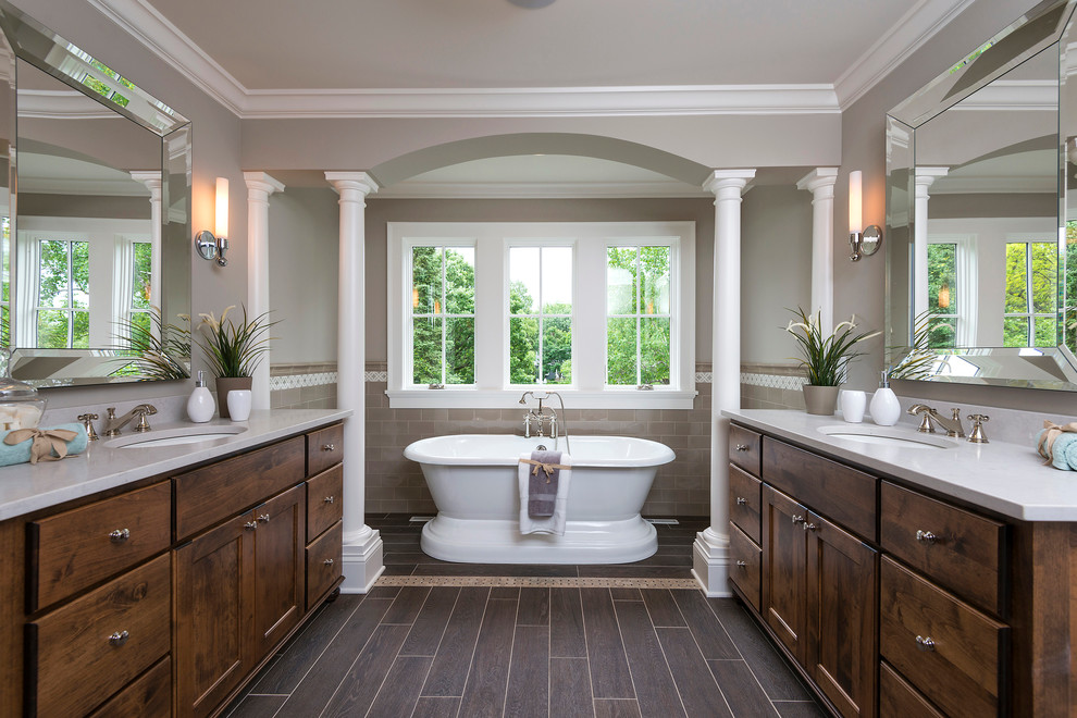 Elegant master beige tile and subway tile dark wood floor freestanding bathtub photo in Minneapolis with an undermount sink, recessed-panel cabinets, dark wood cabinets and gray walls