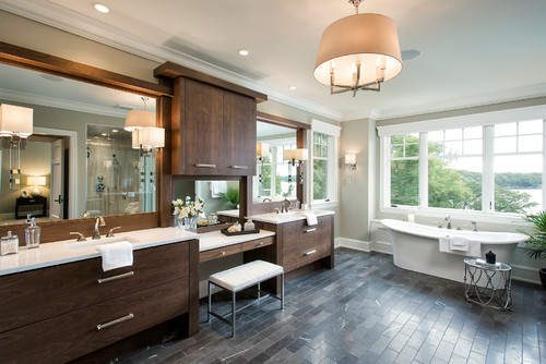 Luxury bathroom with dark wood double vanities, makeup station, and freestanding bathtub by large windows