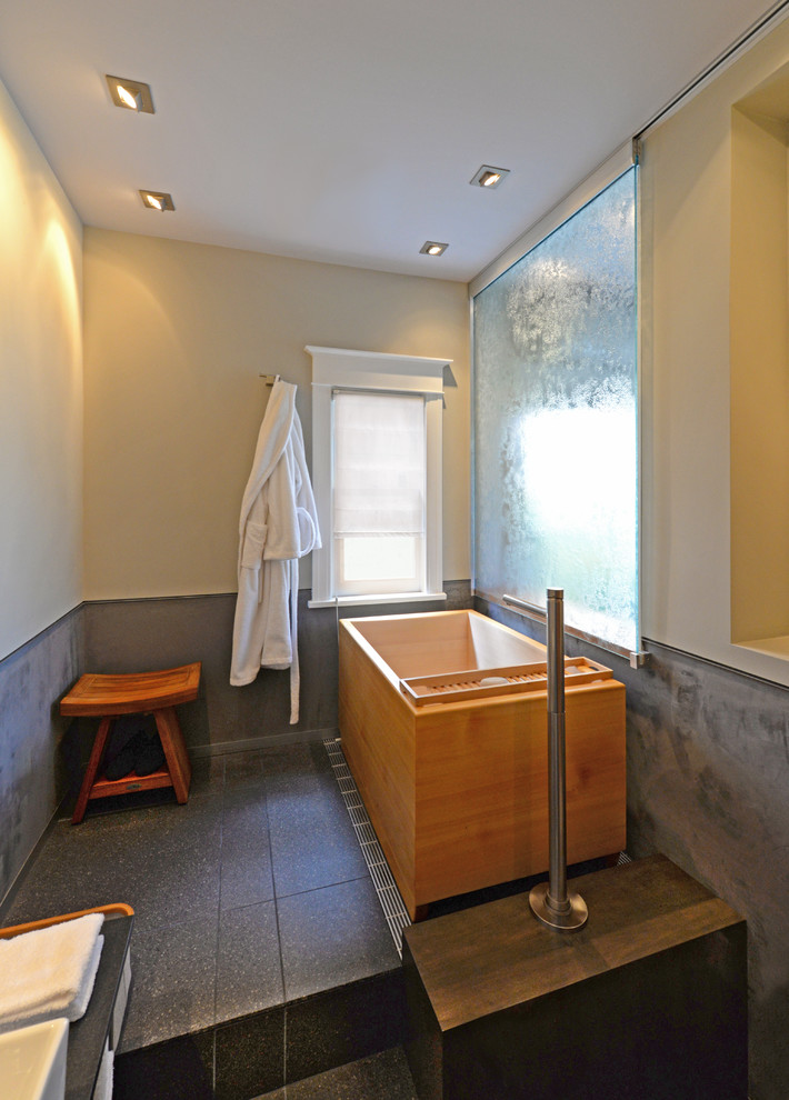 Cette photo montre une petite salle d'eau asiatique en bois foncé avec une vasque, un placard en trompe-l'oeil, un plan de toilette en granite, un bain japonais, WC suspendus, un carrelage noir, des carreaux de porcelaine, un mur gris et un sol en carrelage de porcelaine.