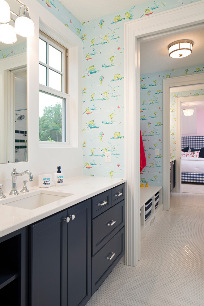 Cette image montre une salle de bain marine pour enfant avec un placard à porte plane, des portes de placard bleues, une baignoire posée, un combiné douche/baignoire, un carrelage blanc, des carreaux de céramique, un mur multicolore, un sol en carrelage de céramique, un lavabo encastré et un plan de toilette en quartz modifié.