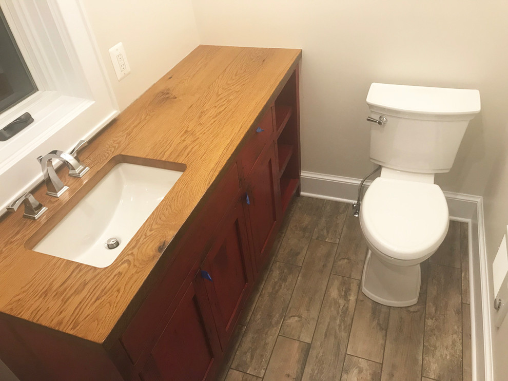 Cette photo montre une petite salle de bain nature avec un placard à porte shaker, des portes de placard rouges, un mur beige, carreaux de ciment au sol, un lavabo encastré et un plan de toilette en bois.