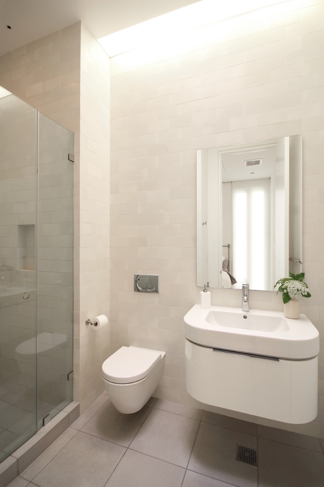 Cette image montre une salle de bain principale minimaliste de taille moyenne avec un lavabo suspendu, un plan de toilette en verre, une douche d'angle, WC à poser, un carrelage blanc, des carreaux de céramique, un mur blanc et un sol en carrelage de porcelaine.