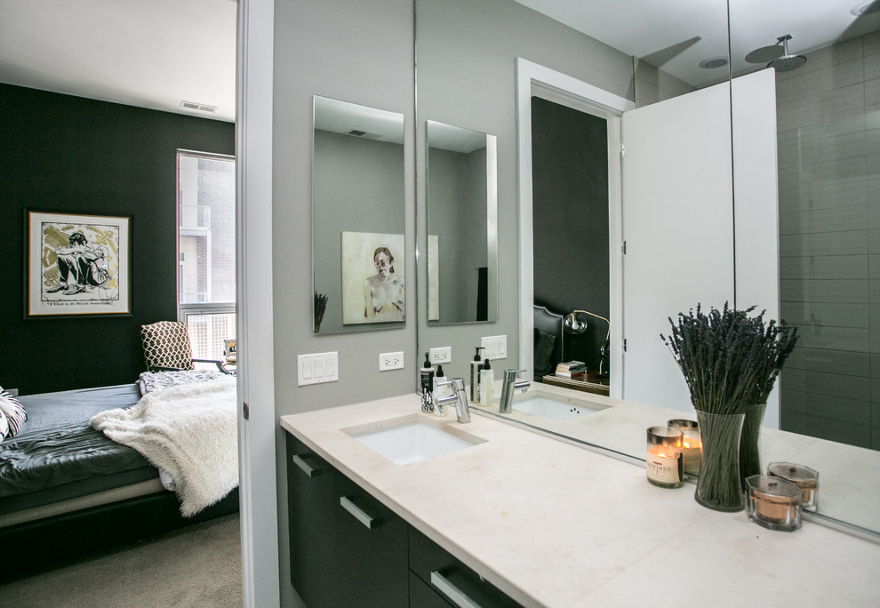 This is an example of a medium sized contemporary bathroom in Chicago with flat-panel cabinets, black cabinets, a one-piece toilet, white tiles, ceramic tiles, beige walls, ceramic flooring, a submerged sink, engineered stone worktops, white floors and a hinged door.