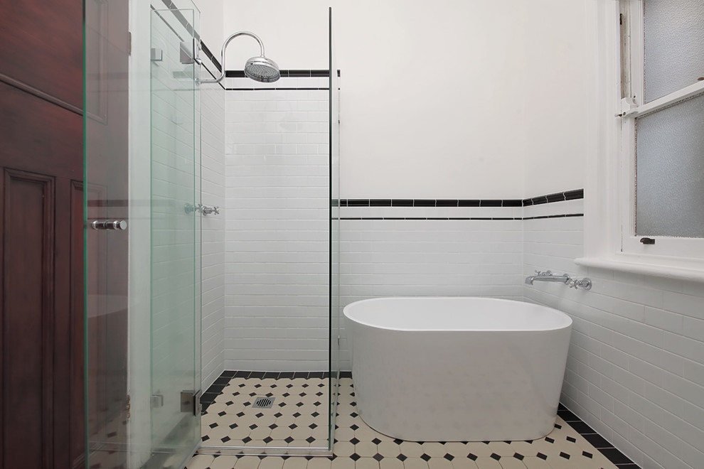 Пример оригинального дизайна: маленькая ванная комната в стиле кантри с стеклянными фасадами, темными деревянными фасадами, отдельно стоящей ванной, угловым душем, раздельным унитазом, белой плиткой, цементной плиткой, белыми стенами, полом из керамогранита, душевой кабиной, раковиной с пьедесталом, черным полом и душем с распашными дверями для на участке и в саду