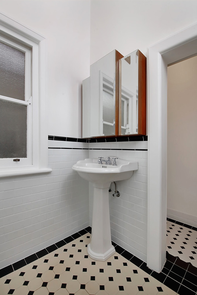 Bild på ett litet amerikanskt vit vitt badrum med dusch, med luckor med glaspanel, bruna skåp, ett fristående badkar, en hörndusch, en toalettstol med separat cisternkåpa, vit kakel, cementkakel, vita väggar, cementgolv, ett piedestal handfat, träbänkskiva, svart golv och dusch med gångjärnsdörr
