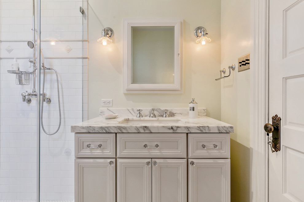 Exempel på ett litet klassiskt badrum med dusch, med vita skåp, en dusch i en alkov, vit kakel, tunnelbanekakel, vita väggar, klinkergolv i keramik, ett undermonterad handfat, bänkskiva i kvartsit, vitt golv, dusch med gångjärnsdörr och luckor med infälld panel