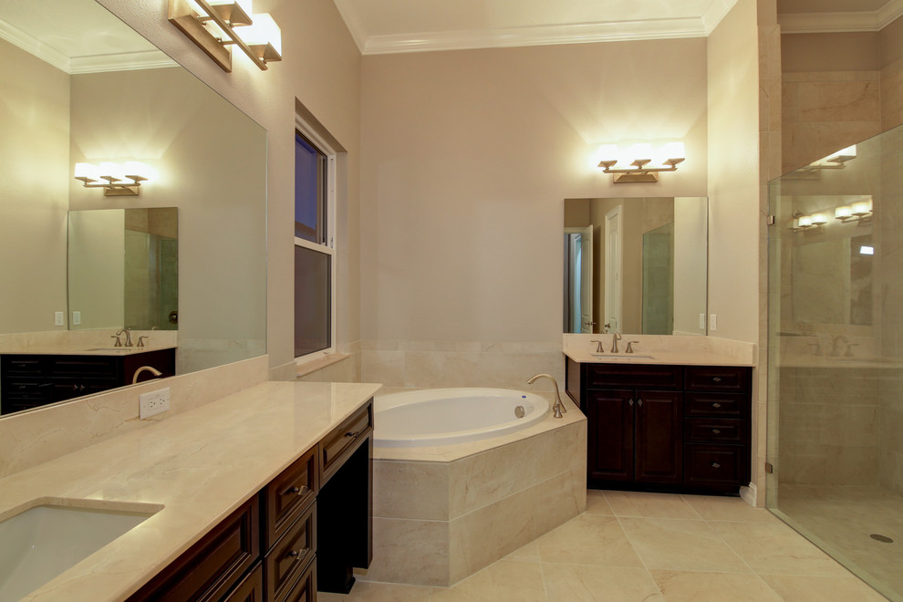 Cette image montre une salle de bain principale traditionnelle en bois foncé de taille moyenne avec un placard avec porte à panneau surélevé, une baignoire d'angle, une douche ouverte, WC séparés, un carrelage beige, des carreaux de céramique, un mur gris, un sol en travertin, un lavabo posé et un plan de toilette en marbre.