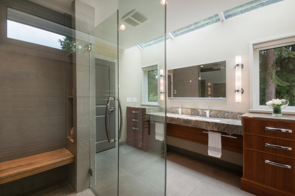 Aménagement d'une grande salle de bain principale classique en bois brun avec une grande vasque, un placard à porte plane, un plan de toilette en onyx, une douche à l'italienne, WC suspendus, un carrelage gris, un carrelage de pierre et un mur blanc.