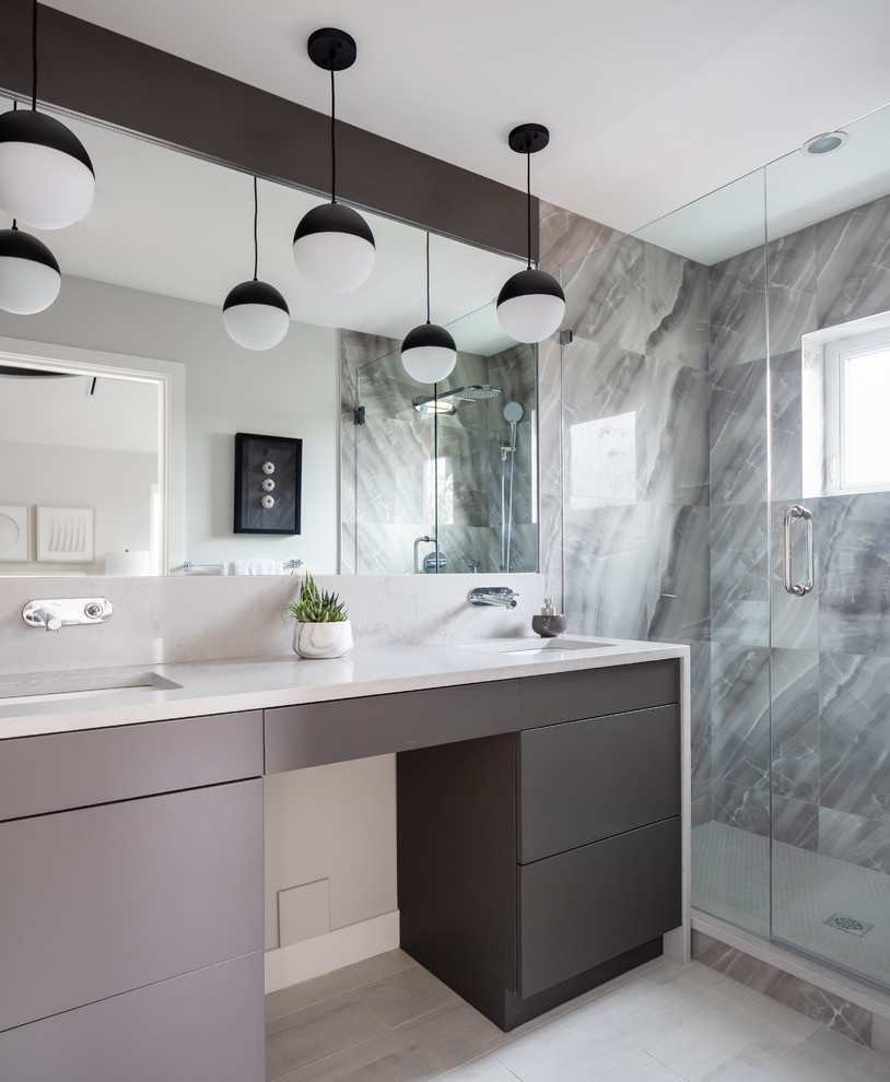 Exemple d'une salle de bain tendance avec un placard à porte plane, des portes de placard grises, un carrelage gris, un mur gris, un lavabo encastré, un sol gris, une cabine de douche à porte battante et un plan de toilette blanc.