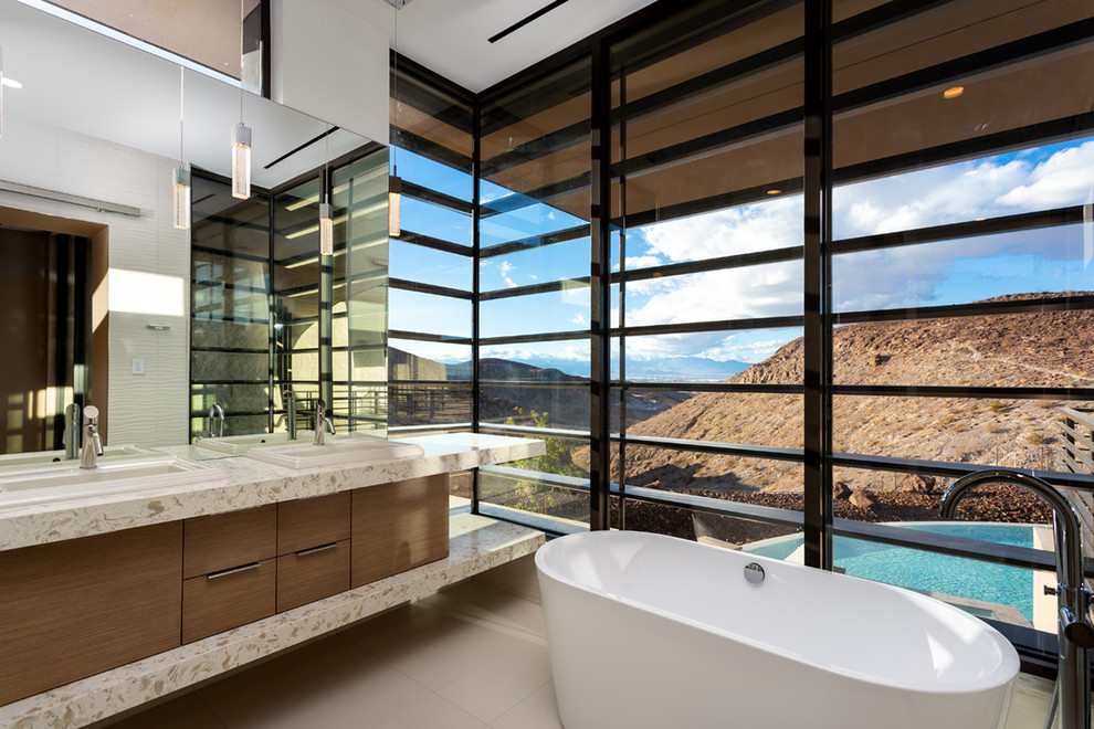 Cette image montre une salle de bain principale design en bois foncé avec un placard à porte plane, une baignoire indépendante, un mur blanc, un lavabo posé, un sol beige et un plan de toilette multicolore.