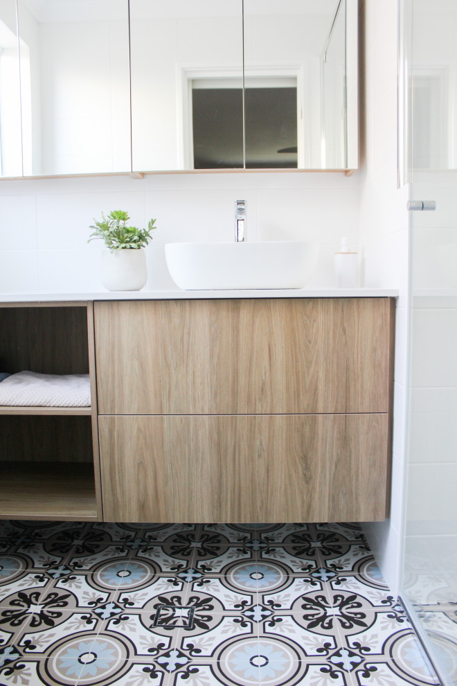 Medium sized retro ensuite bathroom in Perth with open cabinets, dark wood cabinets, an alcove shower, a one-piece toilet, white tiles, ceramic tiles, white walls, porcelain flooring, a vessel sink, engineered stone worktops, blue floors, a hinged door, white worktops, a wall niche, a single sink and a floating vanity unit.