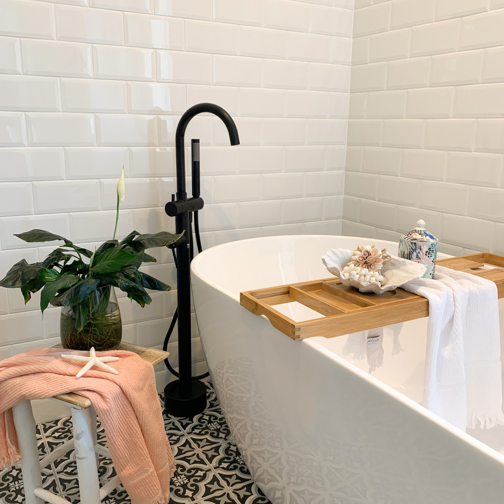 Modern inredning av ett vit vitt en-suite badrum, med vita skåp, ett fristående badkar, en öppen dusch, vit kakel, vita väggar, klinkergolv i keramik, marmorbänkskiva, flerfärgat golv och med dusch som är öppen