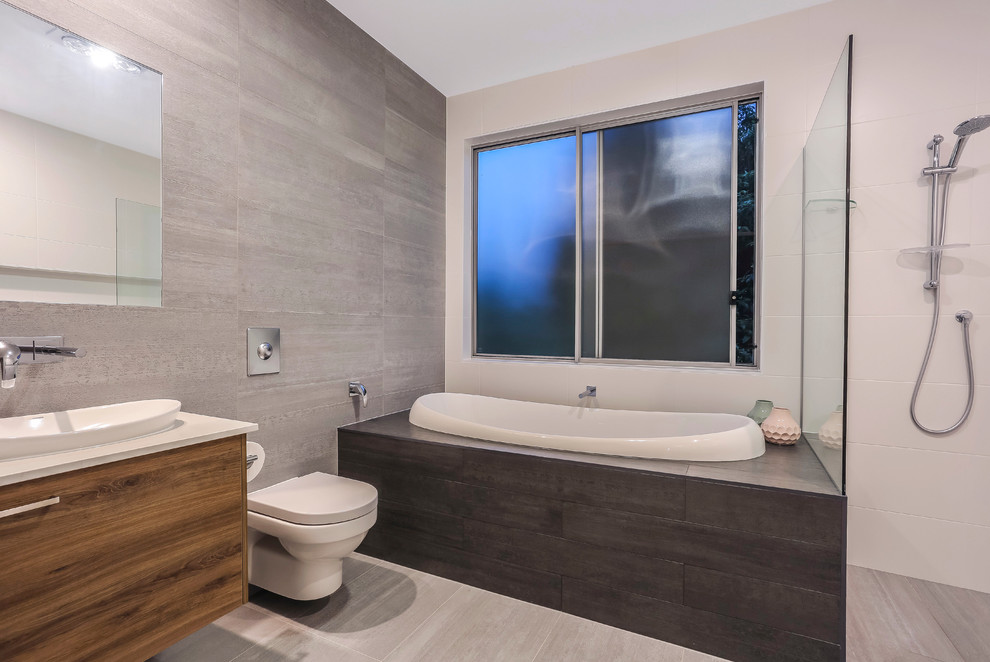 Photo of a medium sized contemporary family bathroom in Brisbane with a built-in bath, an alcove shower, a wall mounted toilet, grey tiles, porcelain tiles, grey walls, porcelain flooring, a built-in sink and engineered stone worktops.