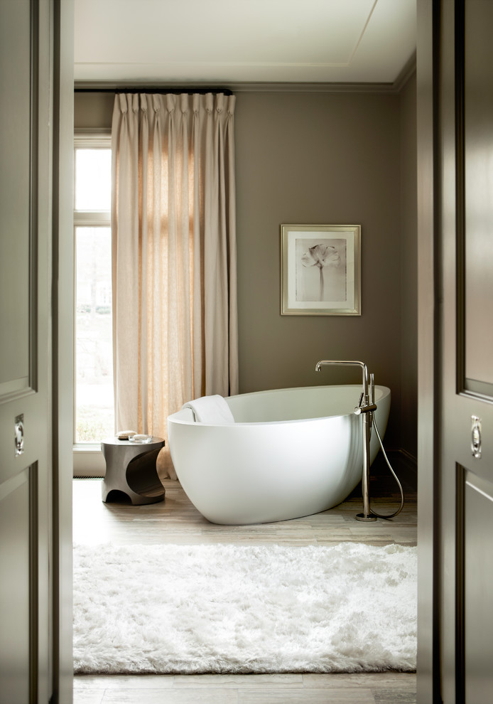 Foto de cuarto de baño principal tradicional renovado con bañera exenta, paredes marrones, suelo de madera clara y suelo beige