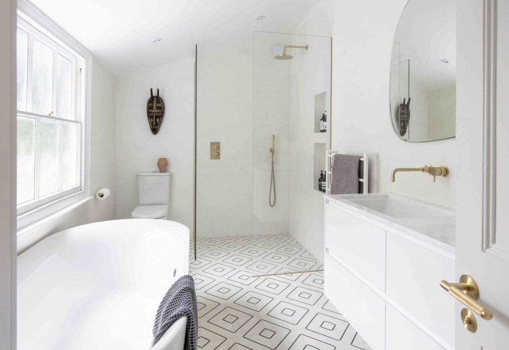 Inspiration for a medium sized scandinavian family bathroom in London with flat-panel cabinets, white cabinets, a freestanding bath, a walk-in shower, a wall mounted toilet, white tiles, white walls, an integrated sink, white floors, an open shower, white worktops, a single sink and a freestanding vanity unit.