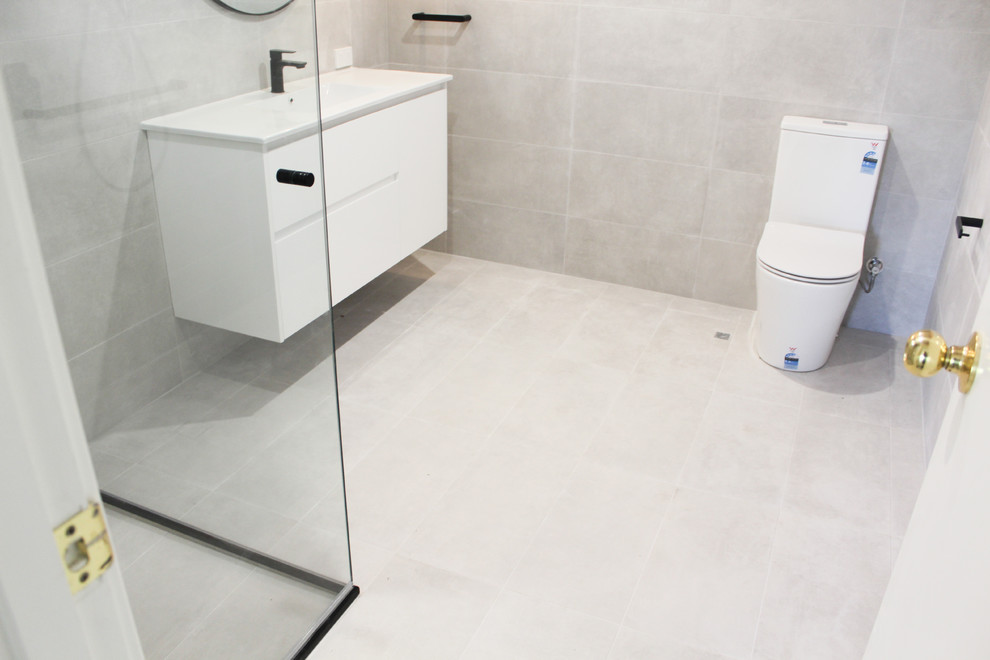This is an example of a large modern ensuite bathroom in Perth with flat-panel cabinets, white cabinets, a corner shower, grey tiles, porcelain tiles, grey walls, porcelain flooring, an integrated sink, stainless steel worktops, grey floors, a hinged door and white worktops.