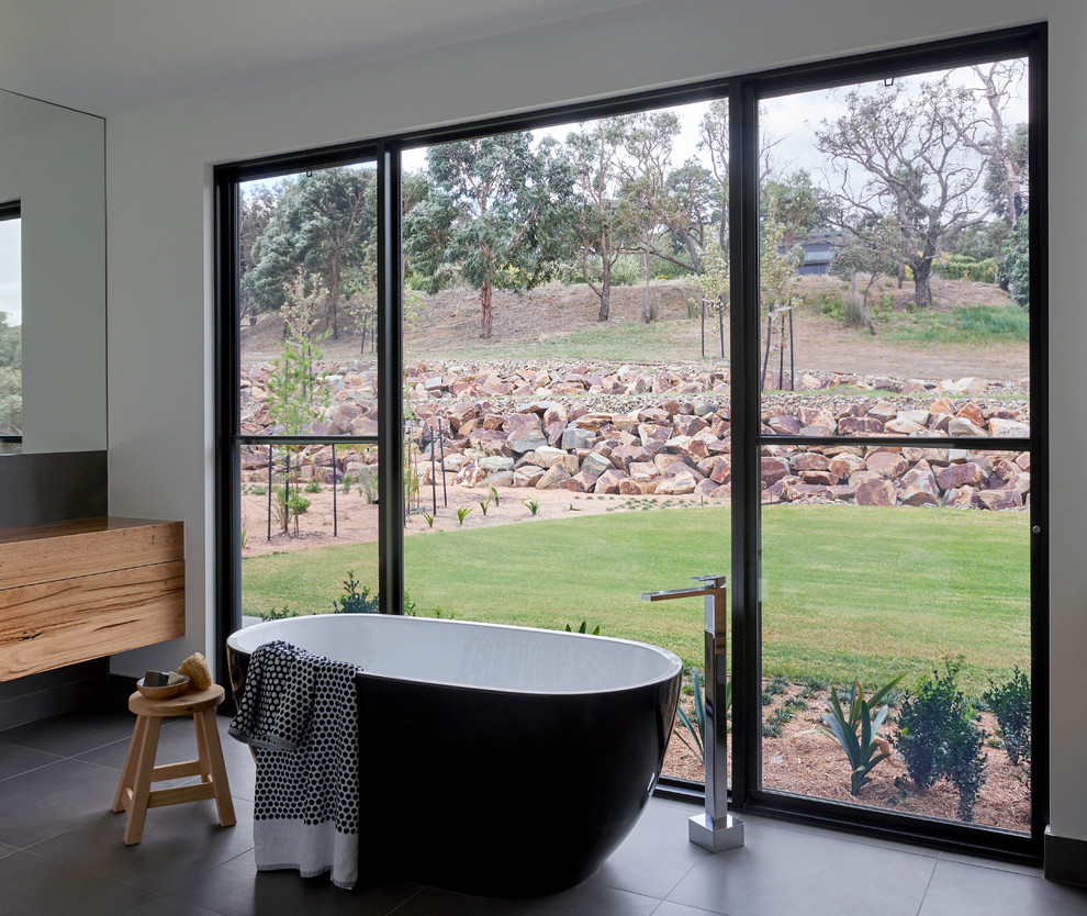 Contemporary bathroom in Other with flat-panel cabinets, medium wood cabinets, a freestanding bath, white walls, wooden worktops, black floors and brown worktops.