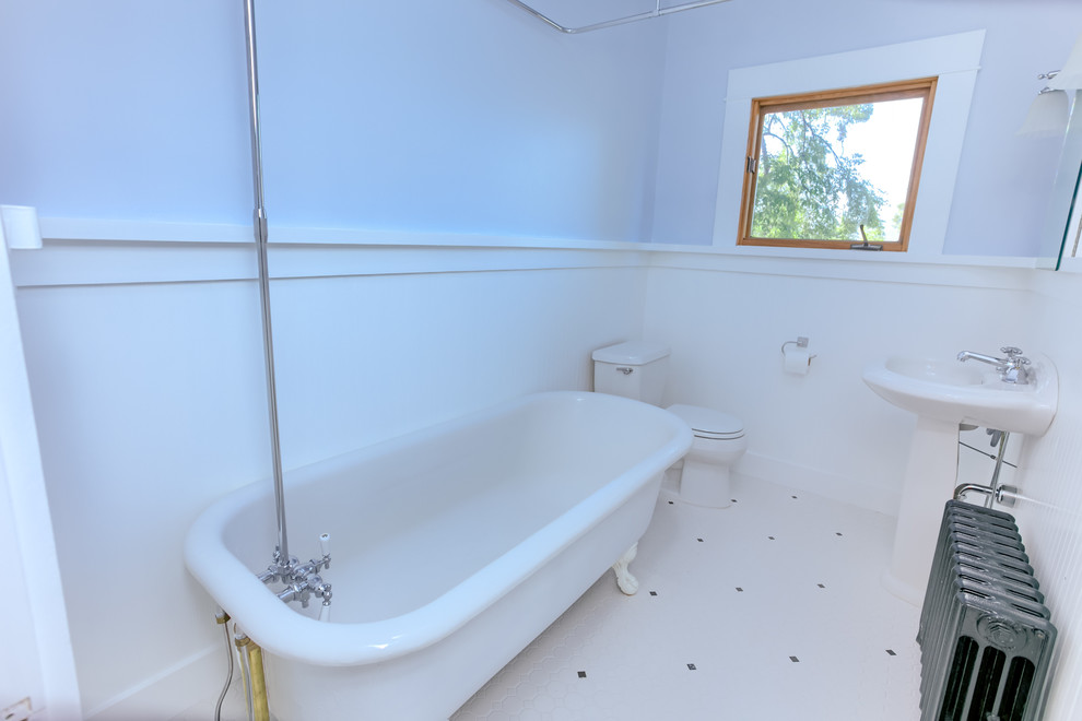 Cette image montre une petite salle de bain principale craftsman avec une baignoire sur pieds, un combiné douche/baignoire, WC séparés, un mur bleu, un lavabo de ferme et un sol blanc.