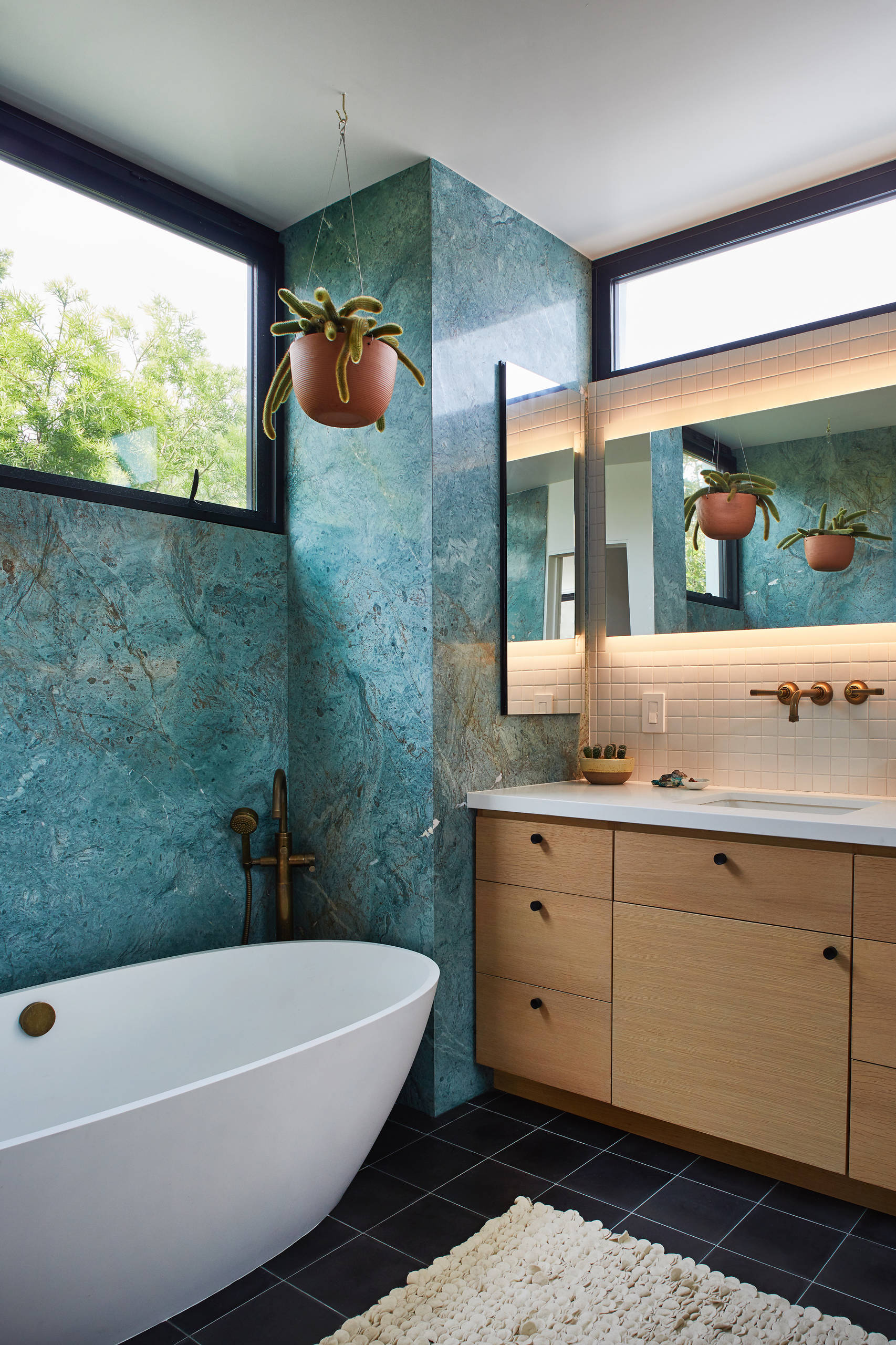 A modern bathroom with a blue cabinet, tile and stone back splash, and  marble tiling the floor / shower. Stock Photo