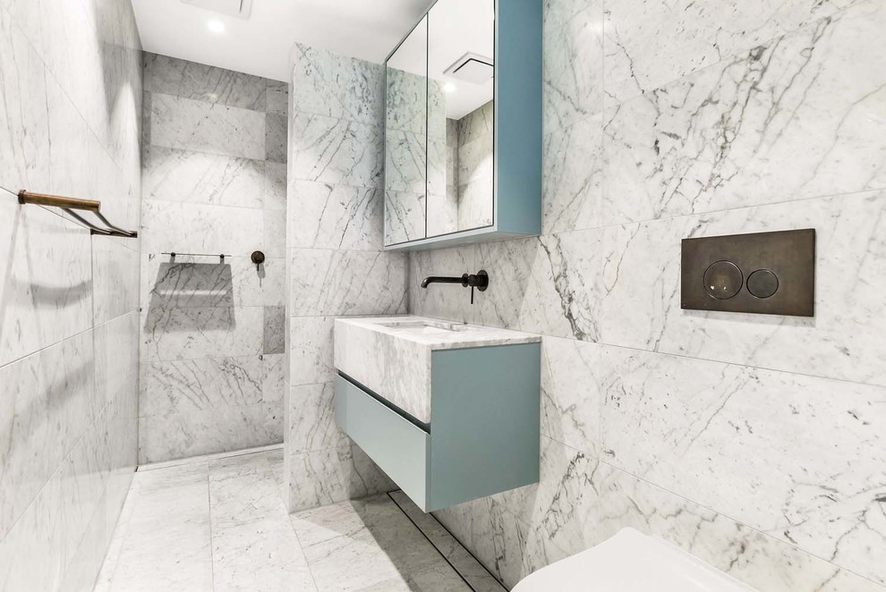Inspiration för ett mellanstort funkis vit vitt en-suite badrum, med blå skåp, en vägghängd toalettstol, grå kakel, vit kakel, marmorkakel, grå väggar, marmorgolv, ett undermonterad handfat, marmorbänkskiva, grått golv, med dusch som är öppen, släta luckor och en kantlös dusch