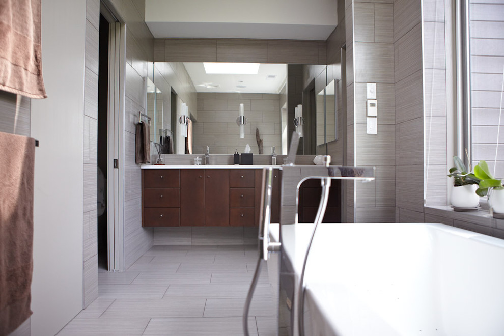 Example of a minimalist gray tile and ceramic tile freestanding bathtub design in Atlanta with an undermount sink, flat-panel cabinets, dark wood cabinets, quartz countertops and a wall-mount toilet