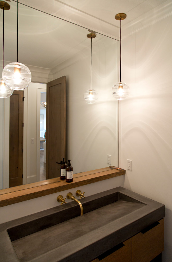 Cette image montre une petite salle d'eau design en bois brun avec un placard à porte plane, un mur beige, une grande vasque et un plan de toilette en béton.