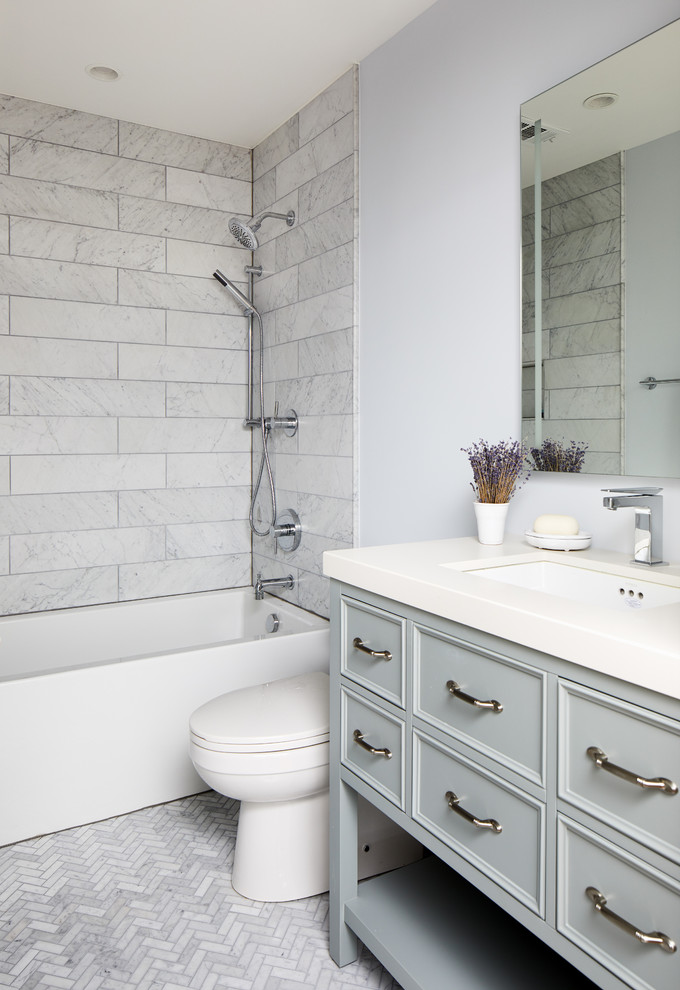 Exemple d'une salle de bain chic de taille moyenne avec un placard avec porte à panneau encastré, des portes de placard bleues, une baignoire en alcôve, un carrelage gris, du carrelage en marbre, un sol en marbre, un plan de toilette en quartz modifié, un sol gris, un mur bleu et un lavabo encastré.