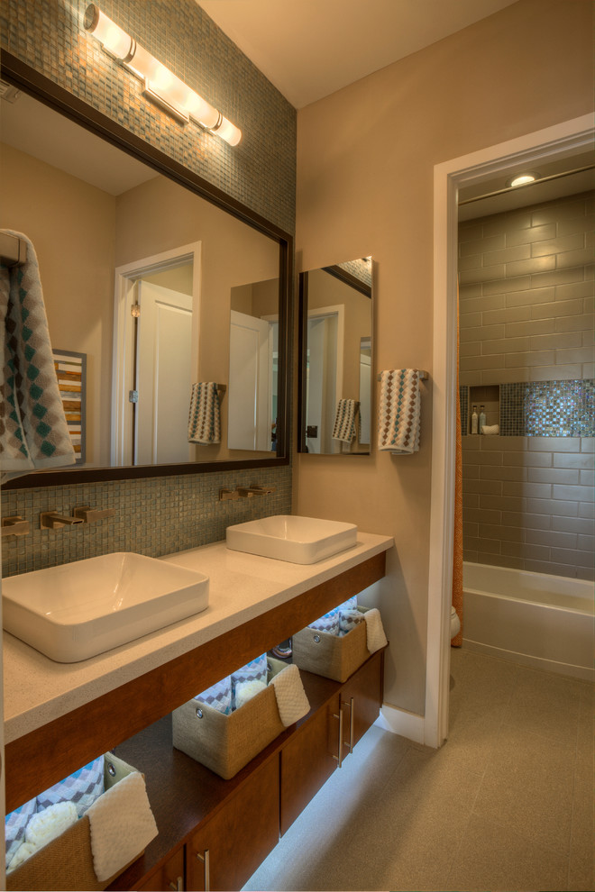 Cette image montre une petite salle de bain traditionnelle en bois brun pour enfant avec une vasque, un plan de toilette en quartz modifié, une baignoire en alcôve, un carrelage bleu, un carrelage en pâte de verre, un mur beige et un sol en carrelage de céramique.
