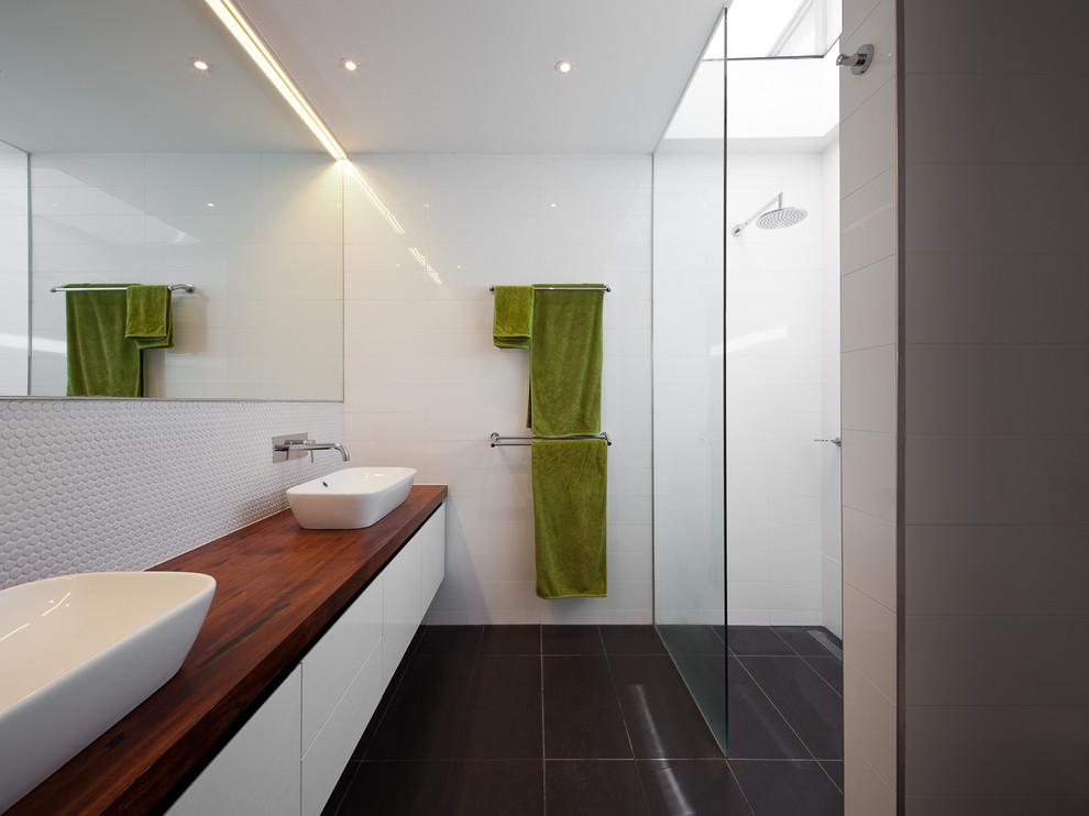 Inspiration for a contemporary bathroom in Melbourne with a vessel sink, wooden worktops, a built-in shower, white tiles, mosaic tiles, white walls, flat-panel cabinets, white cabinets and porcelain flooring.