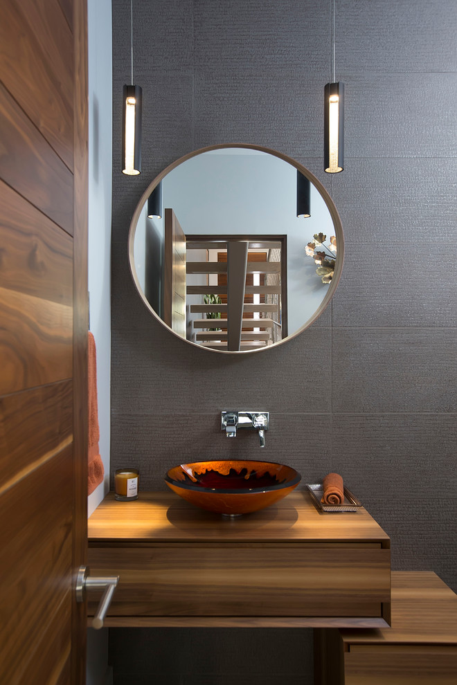 Cette image montre une salle de bain asiatique en bois brun avec un placard à porte plane, un mur gris et une vasque.
