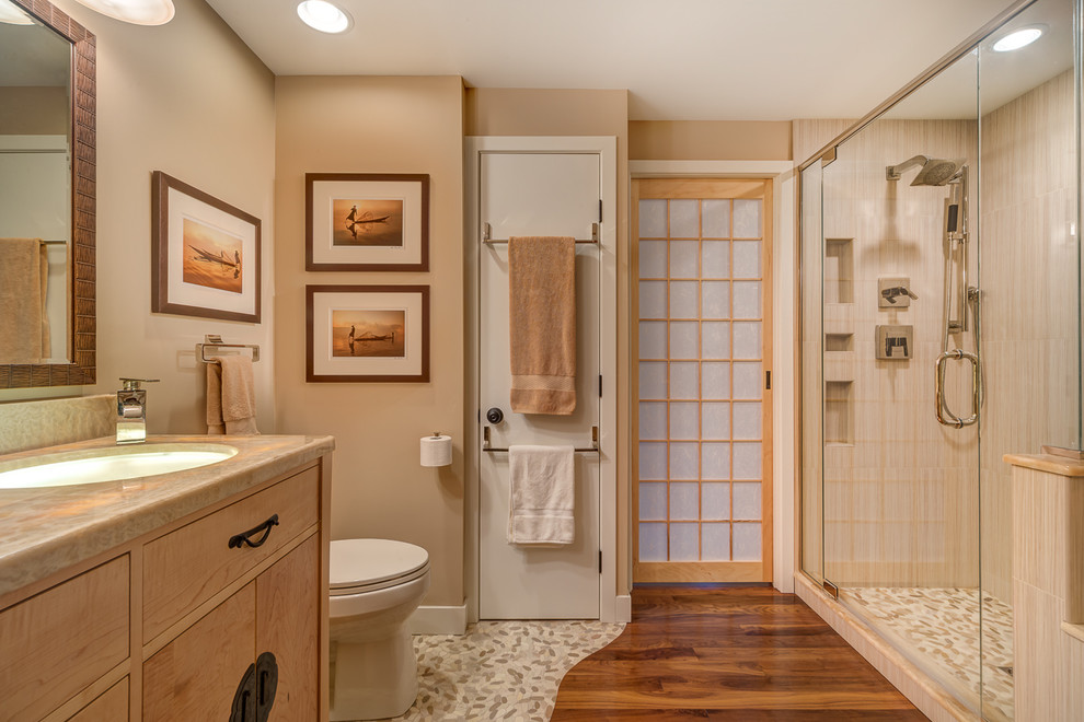 Cette image montre une salle de bain principale asiatique de taille moyenne avec une baignoire posée, une douche d'angle, un carrelage beige, une plaque de galets, parquet foncé et un lavabo encastré.