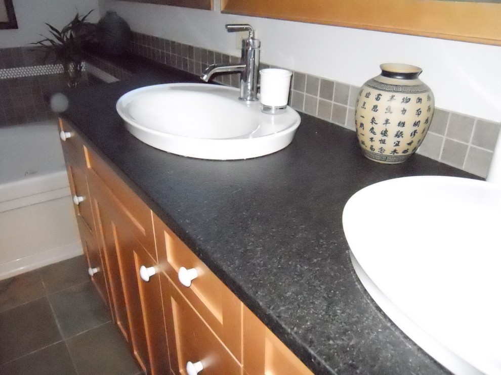 Exemple d'une salle de bain asiatique en bois brun avec un lavabo posé et un carrelage gris.