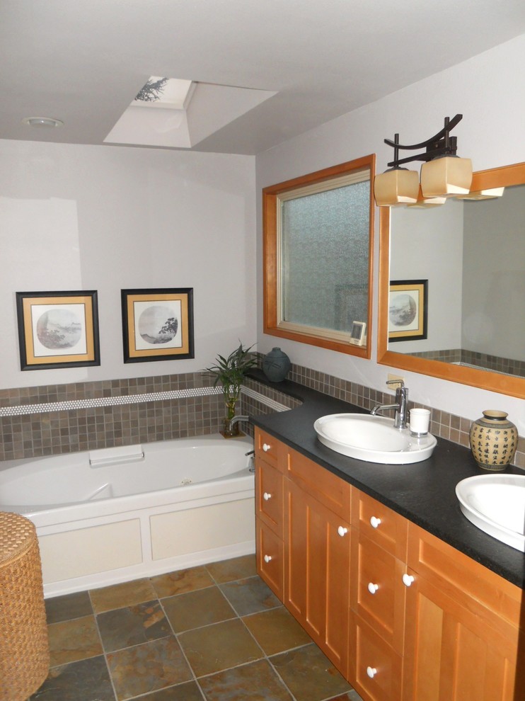 Foto de cuarto de baño asiático con puertas de armario de madera oscura, bañera esquinera y baldosas y/o azulejos grises