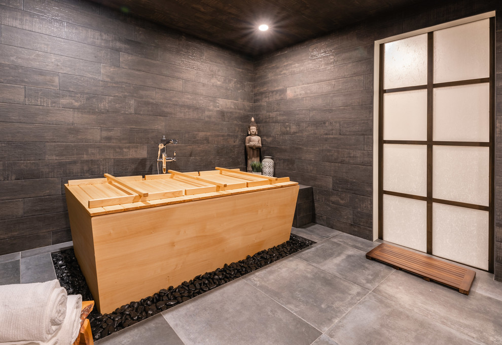 Immagine di una grande sauna etnica con vasca giapponese, zona vasca/doccia separata, piastrelle grigie, piastrelle in gres porcellanato, pareti grigie, pavimento in gres porcellanato, lavabo a bacinella, top in legno e pavimento grigio