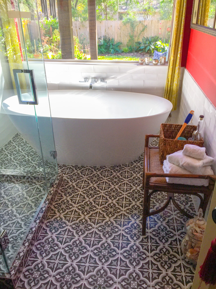 This is an example of a medium sized world-inspired ensuite bathroom in Austin with a freestanding bath, a corner shower, white tiles, cement tiles, red walls, cement flooring, multi-coloured floors and a hinged door.