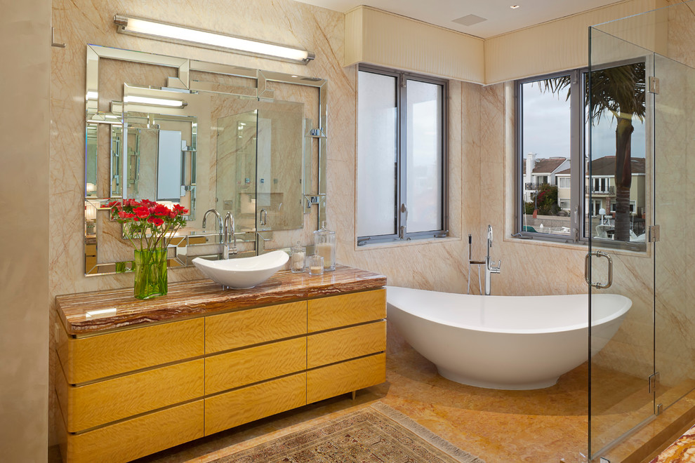 Photo of a contemporary ensuite bathroom in Los Angeles with flat-panel cabinets, medium wood cabinets, a freestanding bath, a corner shower, beige tiles, marble tiles, white walls, limestone flooring, a built-in sink, orange floors, a hinged door, onyx worktops and red worktops.