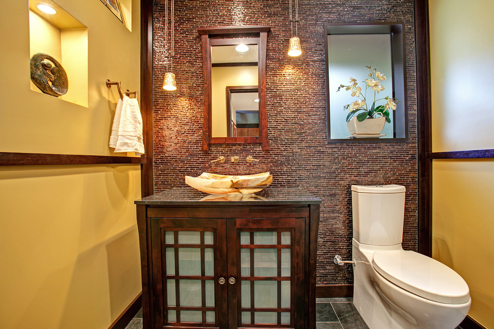 Mittelgroßes Asiatisches Duschbad mit Aufsatzwaschbecken, Glasfronten, dunklen Holzschränken, Granit-Waschbecken/Waschtisch, Wandtoilette mit Spülkasten, gelber Wandfarbe, Schieferboden, braunen Fliesen und Mosaikfliesen in San Diego
