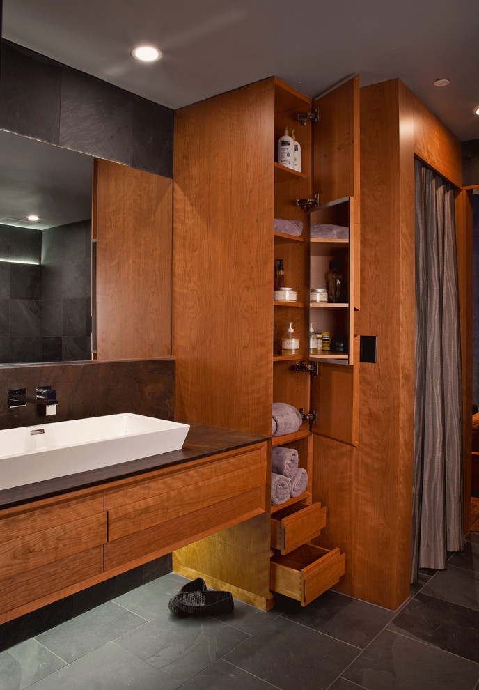Example of a large trendy master slate floor bathroom design in San Diego with a trough sink, furniture-like cabinets, medium tone wood cabinets and limestone countertops