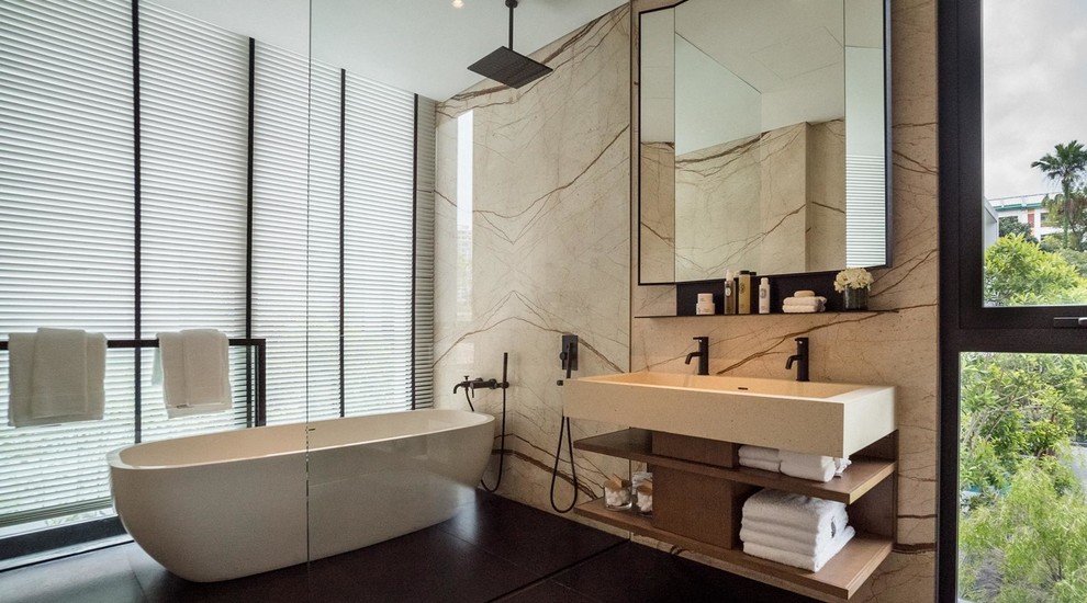 Bild på ett funkis badrum, med öppna hyllor, skåp i mellenmörkt trä, ett fristående badkar, beige väggar, ett avlångt handfat och med dusch som är öppen