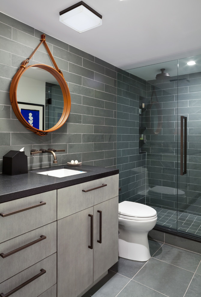 Exempel på ett litet 60 tals badrum med dusch, med ett undermonterad handfat, släta luckor, grå skåp, granitbänkskiva, en dusch i en alkov, en toalettstol med separat cisternkåpa, grå kakel, stenkakel, grå väggar och skiffergolv